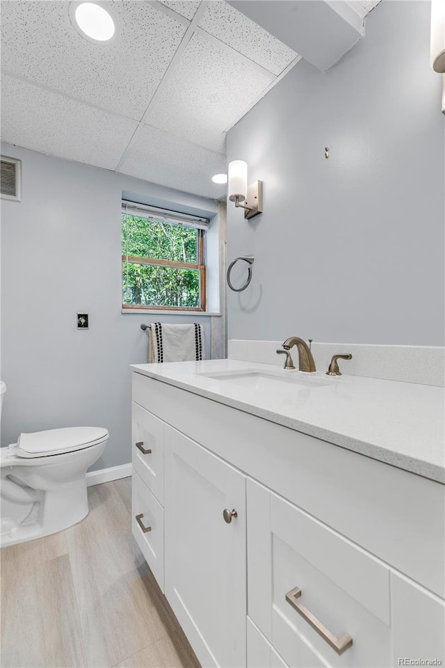 505 S Roosevelt Rd, Lafayette, CO 80026 - half bath with toilet, a drop ceiling, vanity, baseboards, and wood finished floors