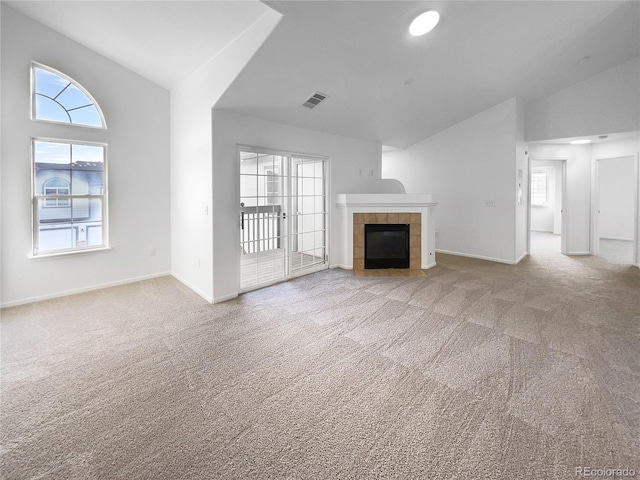 unfurnished living room featuring a fireplace, vaulted ceiling, and light carpet