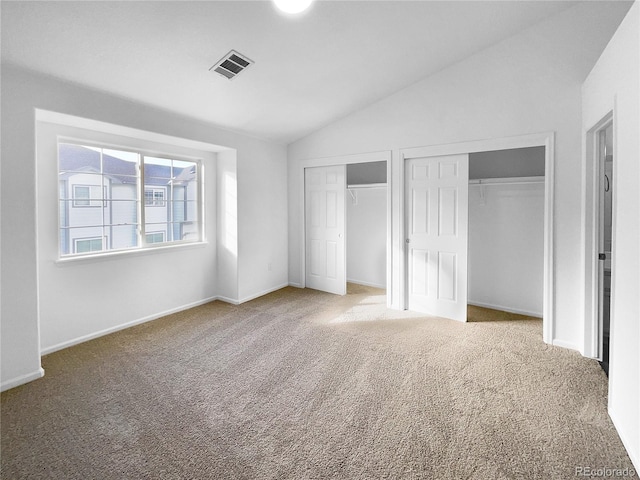 unfurnished bedroom featuring lofted ceiling, carpet floors, and multiple closets