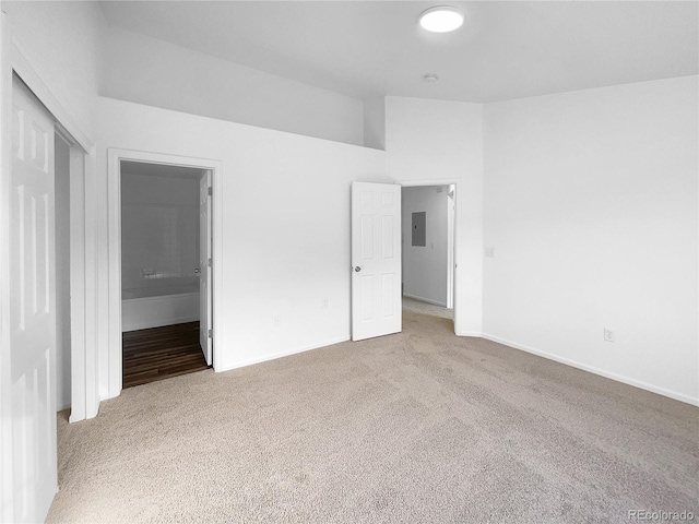 unfurnished bedroom featuring electric panel, ensuite bathroom, a closet, and carpet flooring