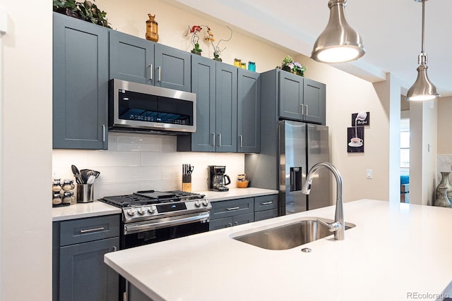 kitchen featuring pendant lighting, sink, backsplash, blue cabinetry, and appliances with stainless steel finishes