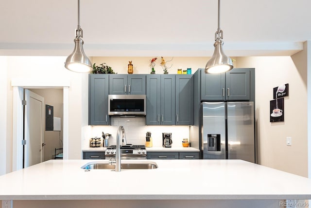 kitchen with an island with sink, decorative backsplash, appliances with stainless steel finishes, and hanging light fixtures