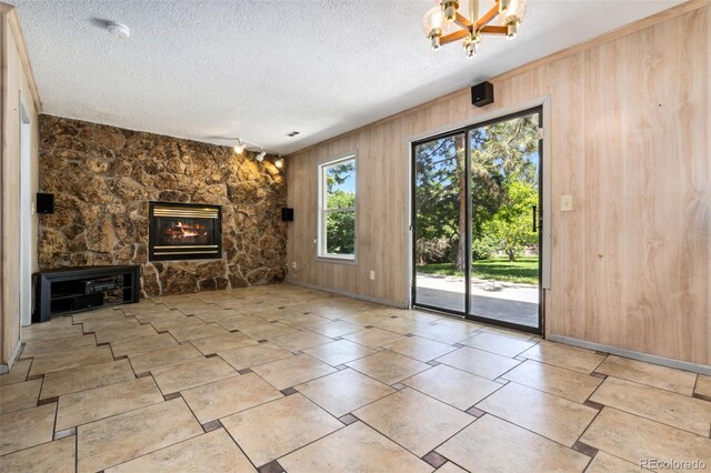 6544 Alkire Ct, Arvada, CO 80004 - unfurnished living room featuring wooden walls, a fireplace, and a textured ceiling
