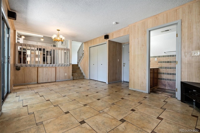 6544 Alkire Ct, Arvada, CO 80004 - unfurnished living room with wooden walls, a chandelier, a textured ceiling, and stairs