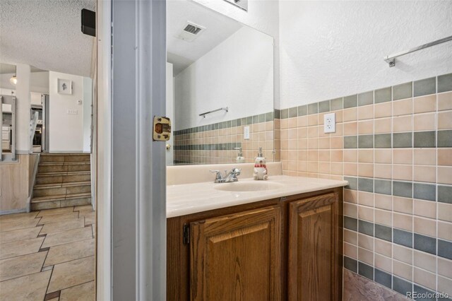 6544 Alkire Ct, Arvada, CO 80004 - bathroom with vanity, tile walls, and a textured ceiling