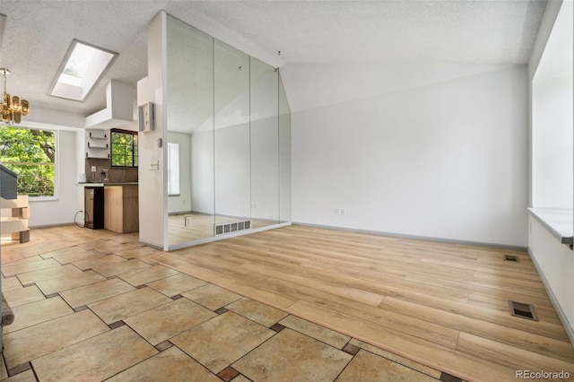 6544 Alkire Ct, Arvada, CO 80004 - empty room with a skylight, a chandelier, vaulted ceiling, and light wood-type flooring