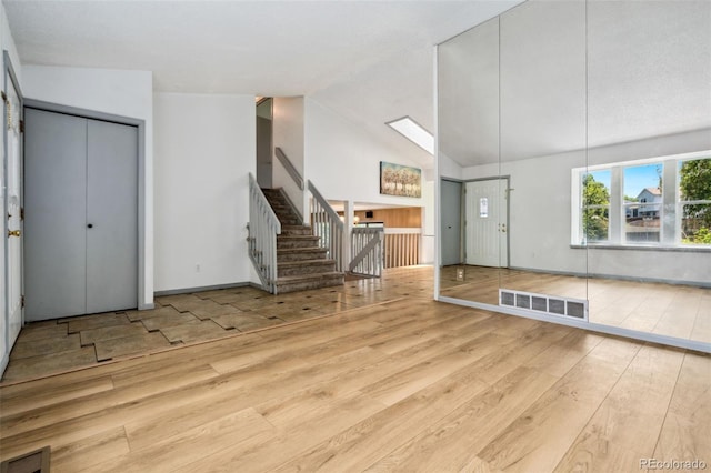 6544 Alkire Ct, Arvada, CO 80004 - unfurnished living room featuring hardwood / wood-style floors, stairway, baseboards, and high vaulted ceiling