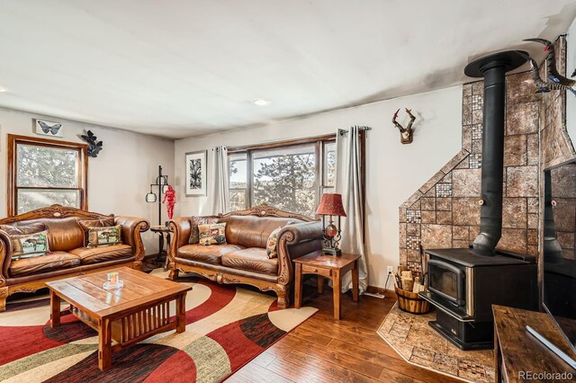 living room featuring a wood stove, baseboards, and hardwood / wood-style floors