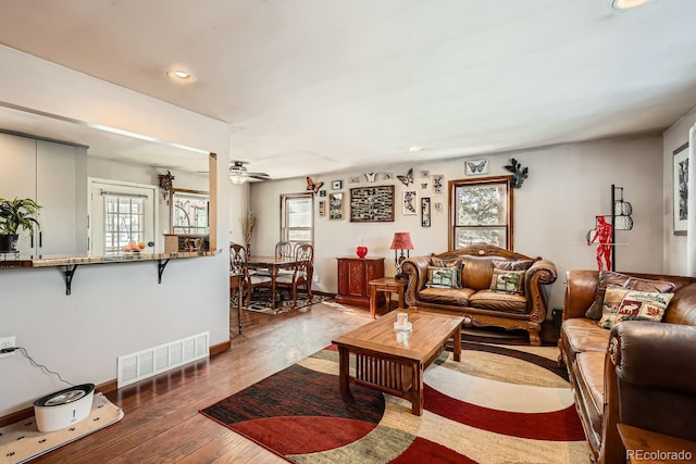 living room with ceiling fan, plenty of natural light, wood finished floors, and visible vents