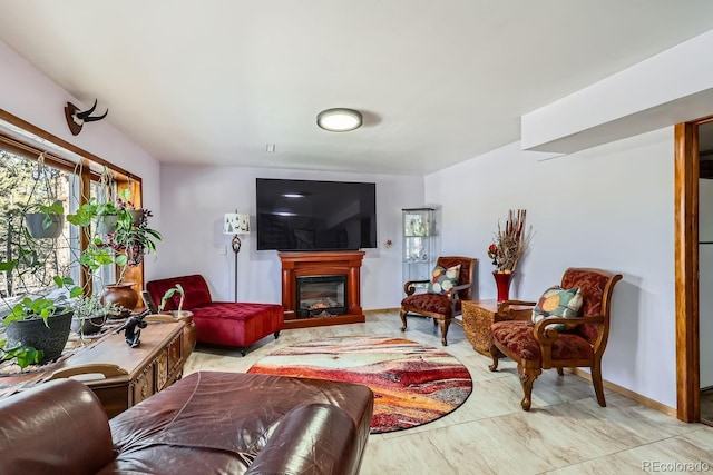 living area with a glass covered fireplace and baseboards