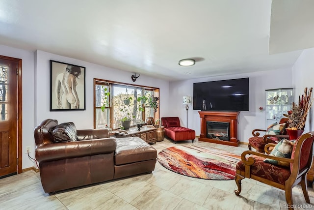 living room featuring a glass covered fireplace and baseboards