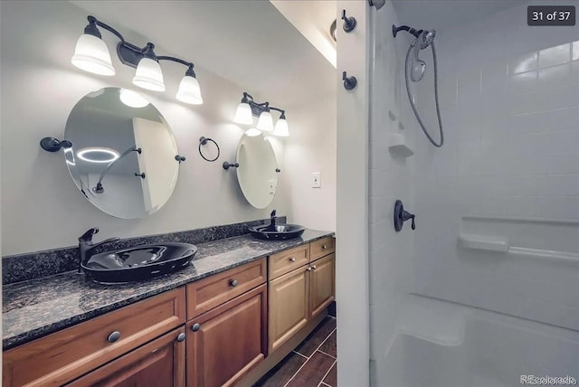 full bath featuring double vanity, walk in shower, and a sink