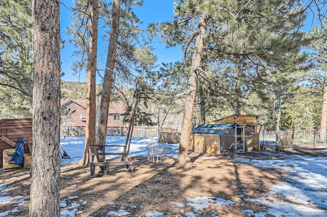 yard covered in snow with an outbuilding, fence, and exterior structure