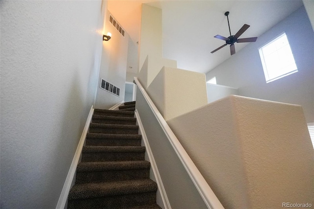 staircase with a towering ceiling and ceiling fan