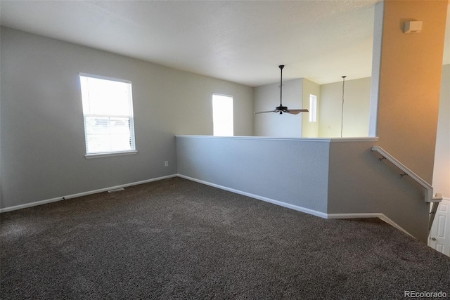 spare room featuring dark colored carpet and ceiling fan