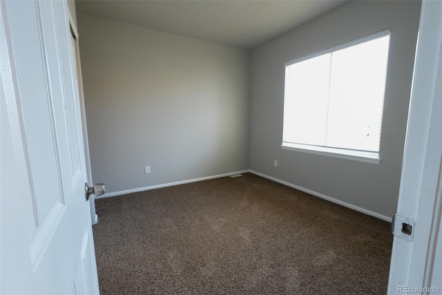 spare room with dark carpet