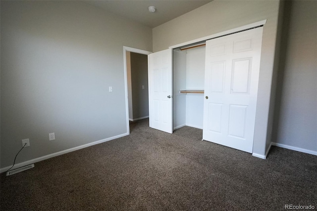 unfurnished bedroom featuring dark colored carpet and a closet