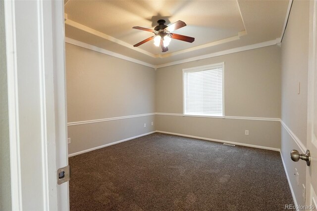 unfurnished room featuring dark colored carpet, ceiling fan, and a tray ceiling