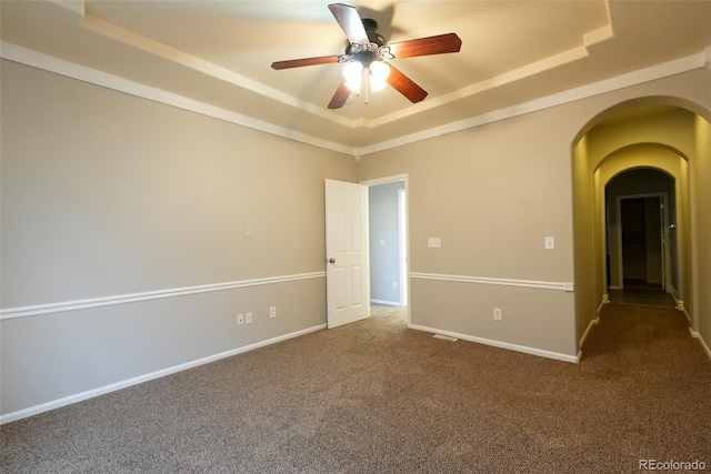 carpeted spare room featuring ceiling fan and a raised ceiling