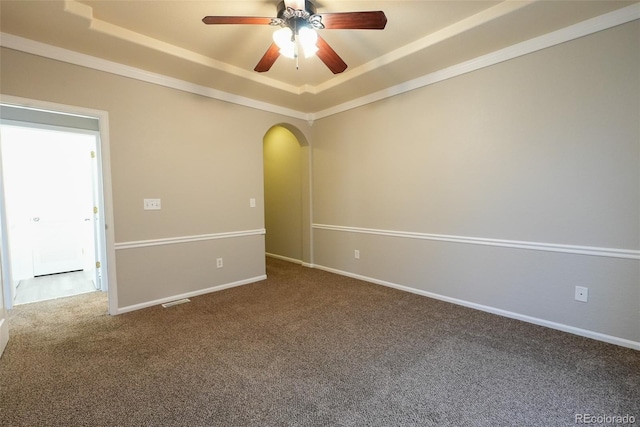 empty room with ceiling fan, carpet flooring, a tray ceiling, and crown molding