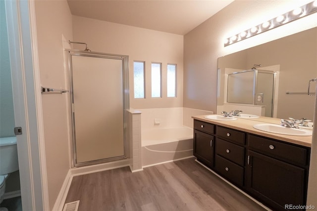 full bathroom with independent shower and bath, toilet, hardwood / wood-style flooring, and dual bowl vanity