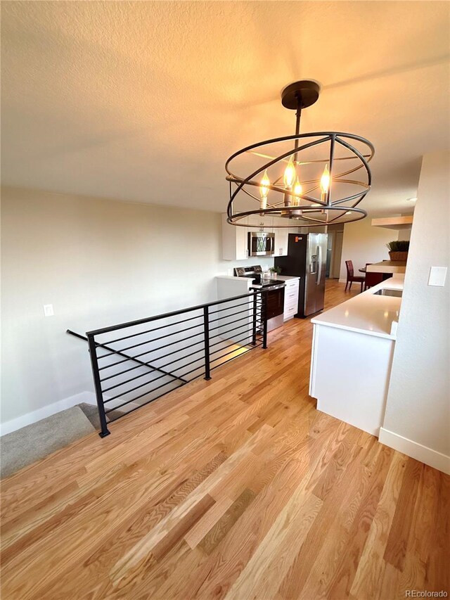 18073 E Belleview Pl, Centennial, CO 80015 - unfurnished dining area featuring a chandelier, light wood-type flooring, baseboards, and a textured ceiling