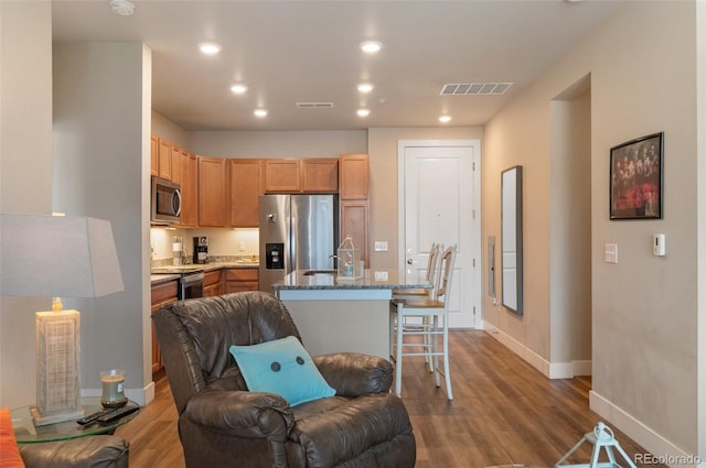 kitchen featuring visible vents, appliances with stainless steel finishes, baseboards, and a breakfast bar area