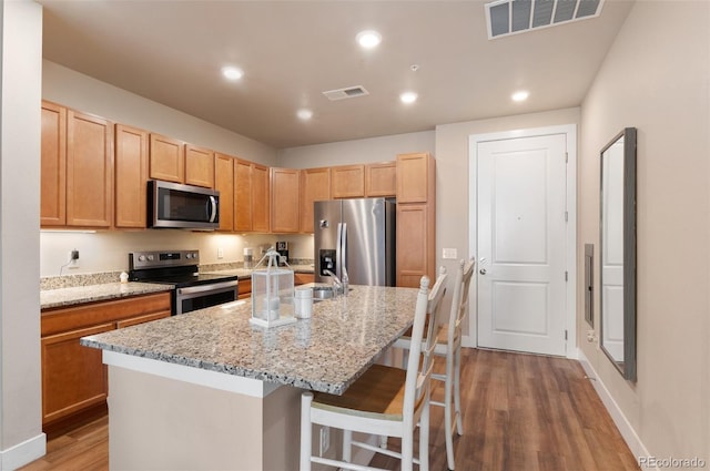 14341 E Tennessee Ave Unit 203, Aurora, CO 80012 - kitchen with appliances with stainless steel finishes, light wood-type flooring, a breakfast bar area, recessed lighting, and light stone counters