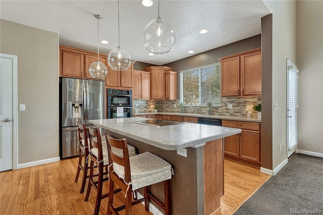 kitchen featuring pendant lighting, a center island, a kitchen breakfast bar, decorative backsplash, and black appliances