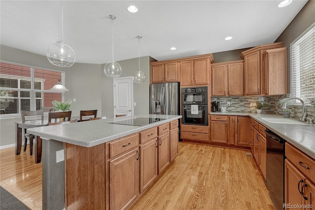 kitchen with backsplash, black appliances, light wood-type flooring, and a sink