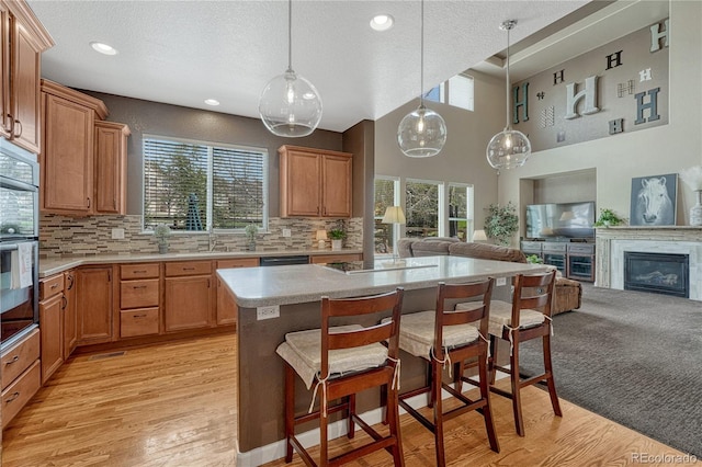 kitchen with a breakfast bar area, a sink, open floor plan, backsplash, and light countertops