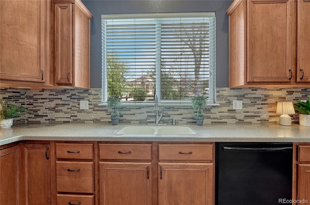 kitchen with backsplash, black dishwasher, light countertops, and a sink