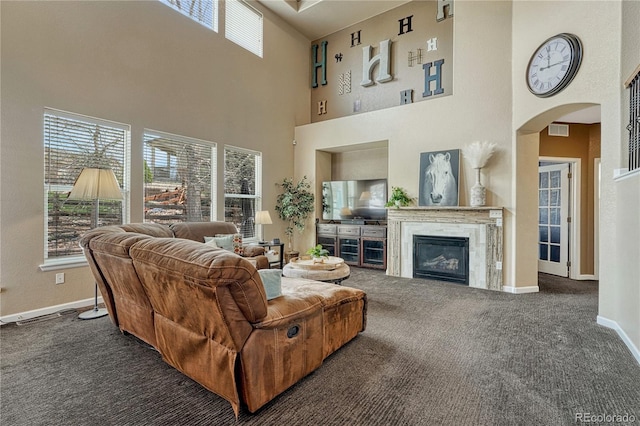 living room featuring carpet, visible vents, arched walkways, a high ceiling, and baseboards