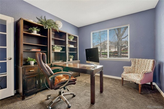carpeted office with baseboards and a textured wall