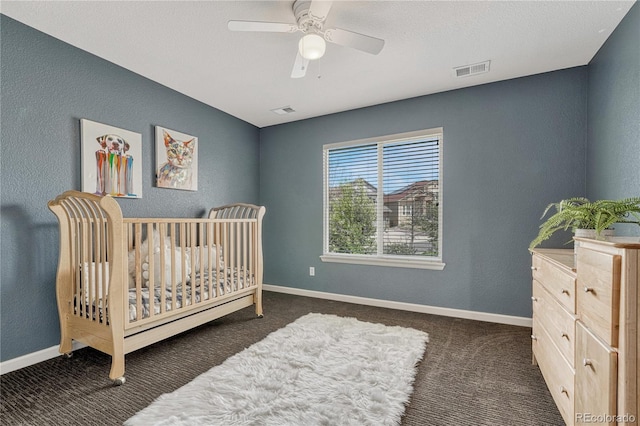 carpeted bedroom featuring baseboards, ceiling fan, visible vents, and a textured wall