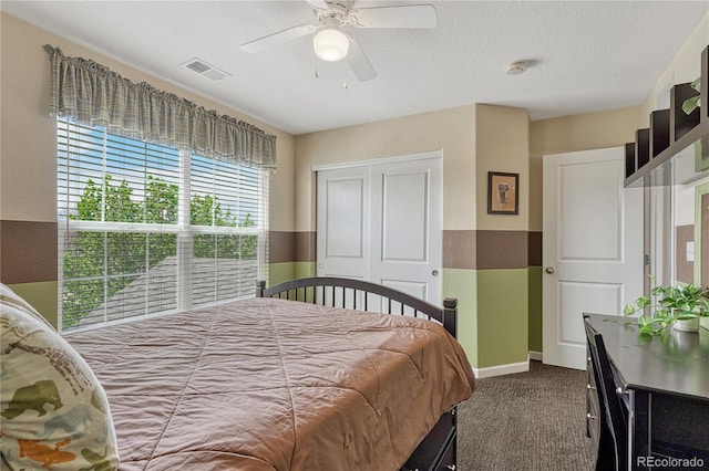 carpeted bedroom with a closet, a textured ceiling, visible vents, ceiling fan, and baseboards