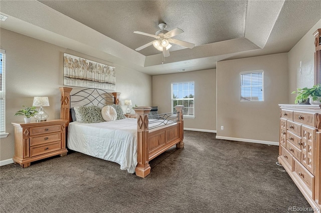 bedroom featuring a tray ceiling, a textured ceiling, baseboards, and dark carpet