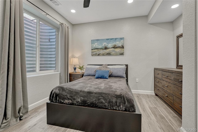 bedroom with baseboards, light wood-type flooring, visible vents, and multiple windows
