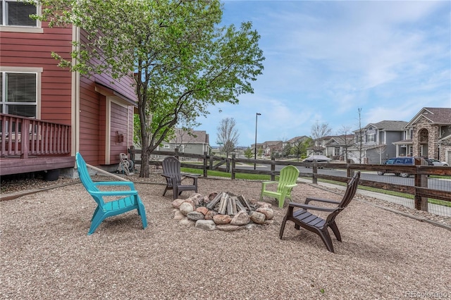 view of yard with a fire pit, fence, a residential view, and a wooden deck