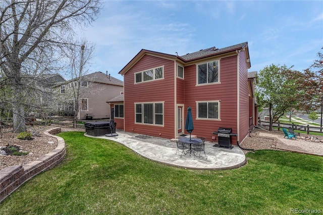 rear view of house with a yard, a patio, and a hot tub