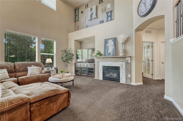22965 Allendale Ave, Parker, CO 80138 - carpeted living room featuring a towering ceiling, arched walkways, and a glass covered fireplace