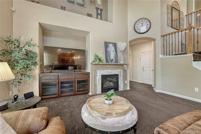 22965 Allendale Ave, Parker, CO 80138 - carpeted living area featuring arched walkways, a towering ceiling, a glass covered fireplace, and stairs