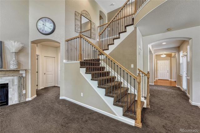 22965 Allendale Ave, Parker, CO 80138 - stairway with carpet flooring, a high ceiling, arched walkways, and a tile fireplace