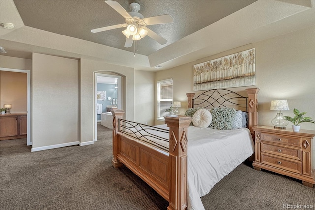 22965 Allendale Ave, Parker, CO 80138 - carpeted bedroom featuring arched walkways, a textured ceiling, a tray ceiling, ensuite bathroom, and a ceiling fan