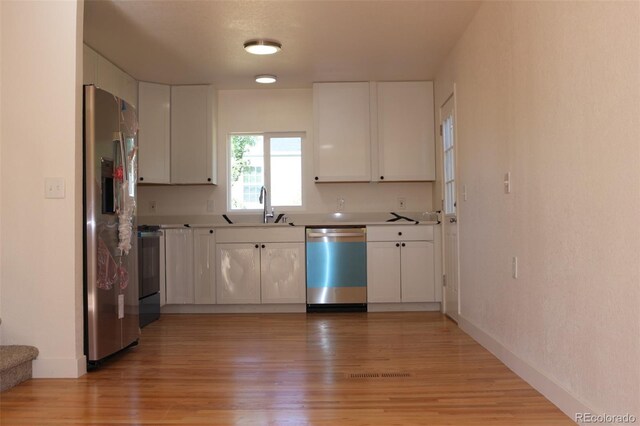 1705 Cathay Ct, Aurora, CO 80011 - kitchen with stainless steel appliances, white cabinetry, light wood-type flooring, and light countertops