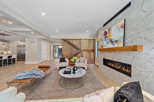 living room with light hardwood / wood-style floors, beam ceiling, and a fireplace