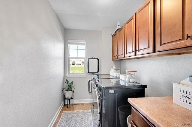 washroom featuring cabinets and washer and clothes dryer