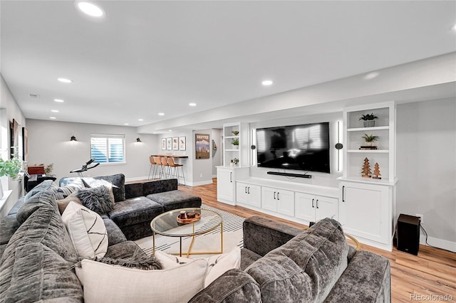 living room with built in features and light hardwood / wood-style flooring