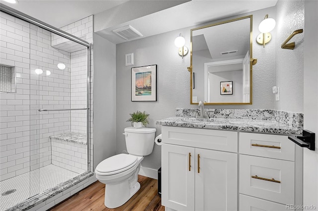 bathroom with hardwood / wood-style flooring, vanity, a shower with door, and toilet