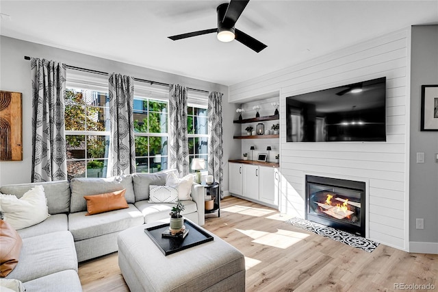 living room with ceiling fan, a fireplace, and light wood-type flooring